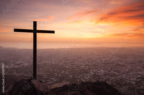 View of the large city Lima (Peru) from the first hills of the Andes, situated between Surco and La Molina, at sunset. A cross is at the summit of the hill.