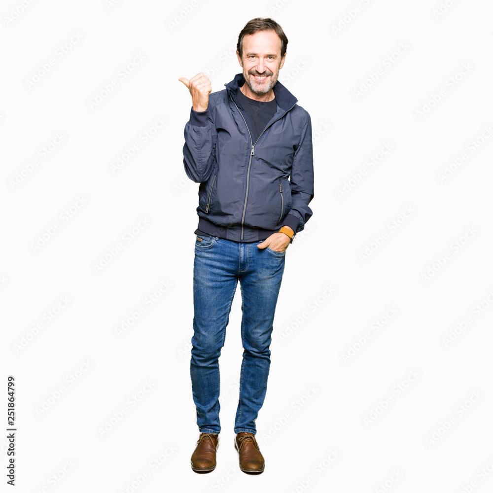 Middle age handsome man wearing a jacket smiling with happy face looking and pointing to the side with thumb up. Middle age handsome man wearing a jacket smiling with happy face looking and pointing to the side with thumb up.
