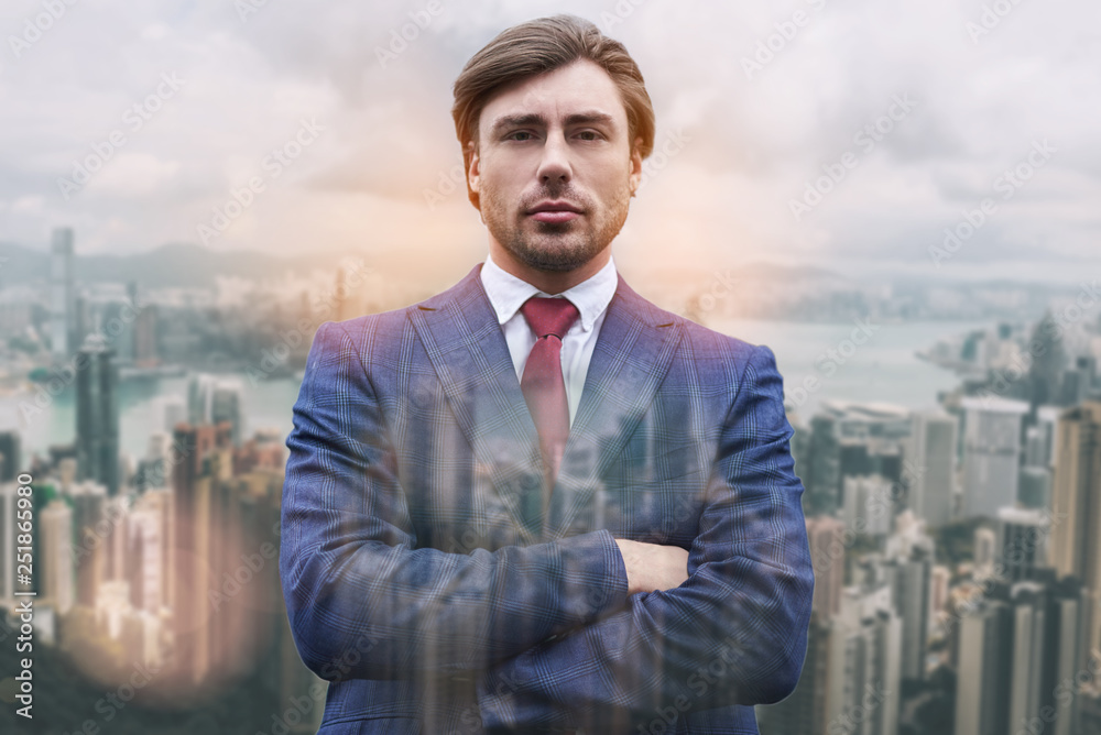 Everything should be perfect! Close-up portrait of handsome businessman keeping his arms crossed while standing against of cityscape background. Everything should be perfect! Close-up portrait of handsome businessman keeping his arms crossed while standing against of cityscape background.
