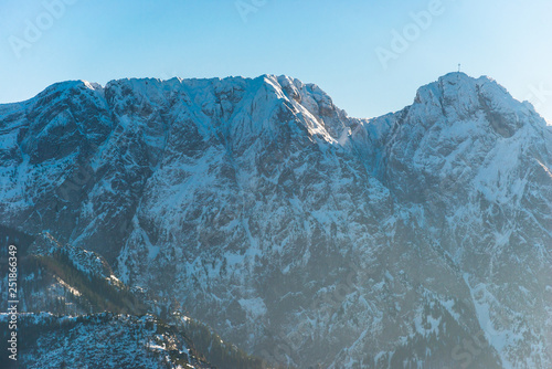 A beautiful view of the Polish Tatra Mountains. Sunny, beautiful day in the winter, snow-capped mountains and blue sky. A visible metal cross on the top of the Great Giewont.