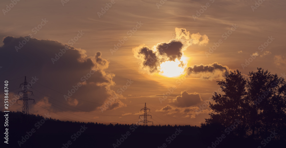 sunset with electricity tower in countryside. Summer  scene. Dusk sky with sun. Spring sunset