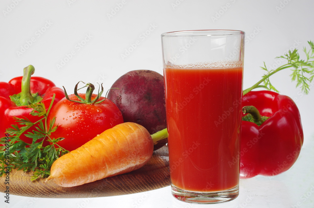 Carrots, beets, tomatoes and a glass of vegetable juice.