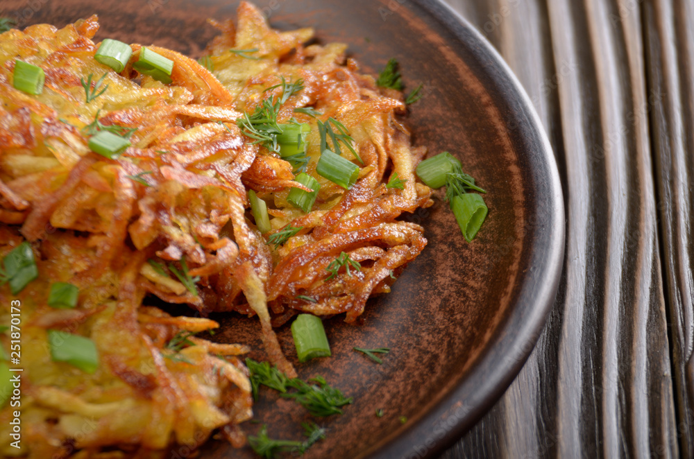 Fresh homemade tasty potato pancakes in clay dish on rustic wooden table Fresh homemade tasty potato pancakes in clay dish on rustic wooden table