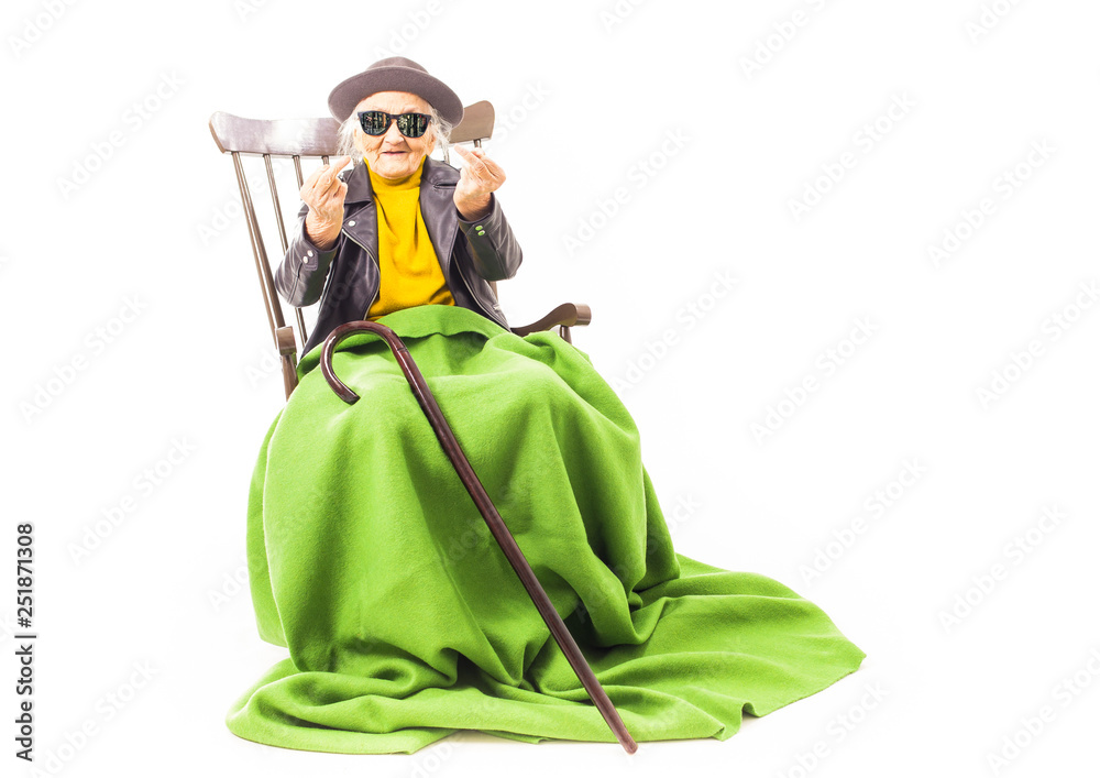 Old woman with sunglasses sitting on a chair.