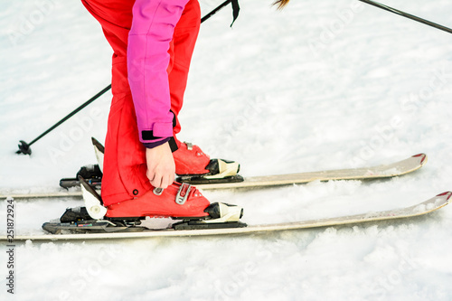 Woman in red-pink clothes wearing ski footwear for skiing