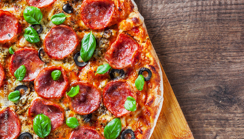 Pepperoni Pizza with Mozzarella cheese, salami, Tomatoes, olive, pepper, Spices and Fresh Basil. Italian pizza on wooden table background