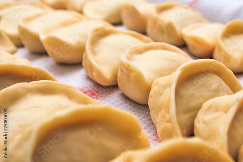 Raw meat pelmeni, ravioli, dumplings top view on a wooden board