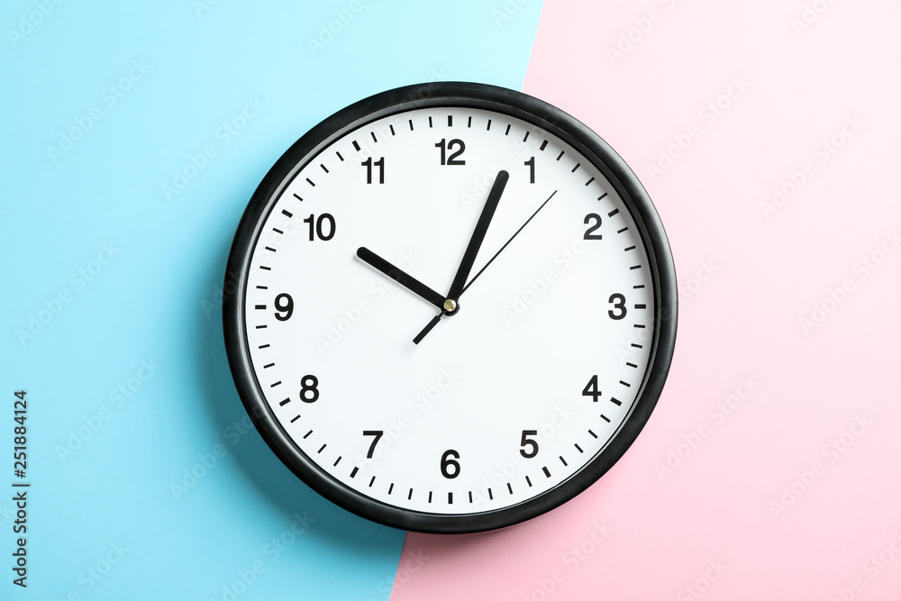Big beautiful office clock on two tone solid color pink and light blue background Big beautiful office clock on two tone solid color pink and light blue background