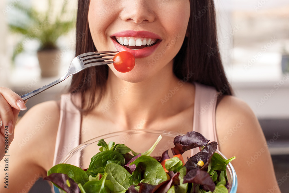 Young girl at kitchen healthy lifestyle standing with bowl eating salad happy face close-up Young girl at kitchen healthy lifestyle standing with bowl eating salad happy face close-up