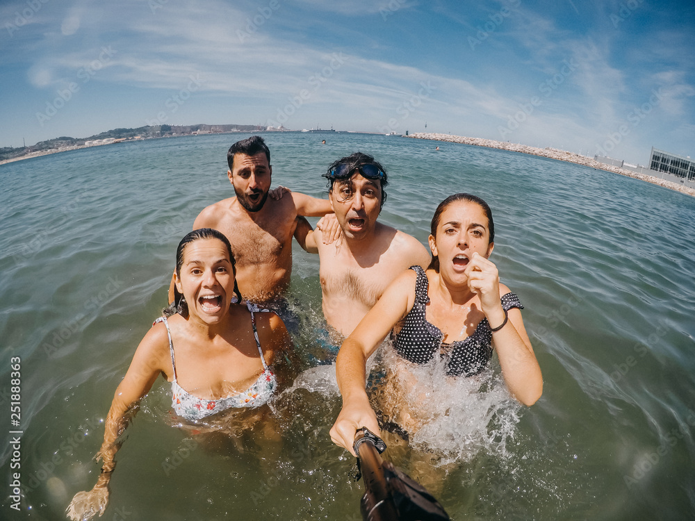 .Funny group of friends taking pictures together and playing in the water on the beach. Enjoying a summer day in north of Spain. Lifestyle .Funny group of friends taking pictures together and playing in the water on the beach. Enjoying a summer day in north of Spain. Lifestyle
