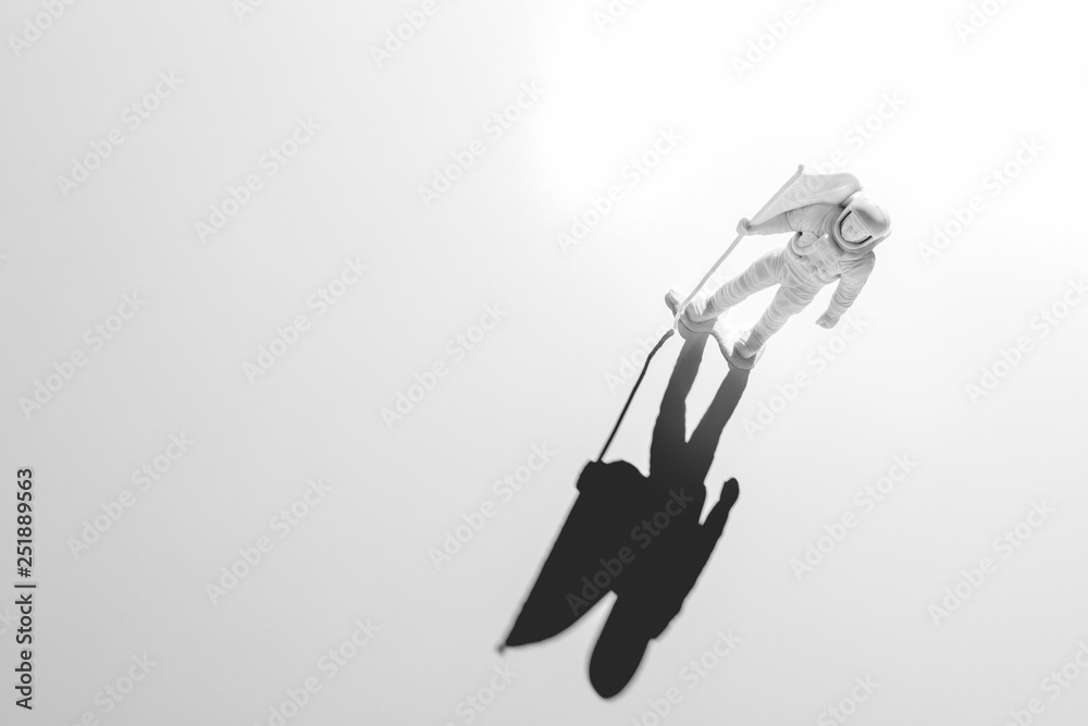Lone Generic White Astronaut Figurine with American Flag in dramatic lighting Lone Generic White Astronaut Figurine with American Flag in dramatic lighting