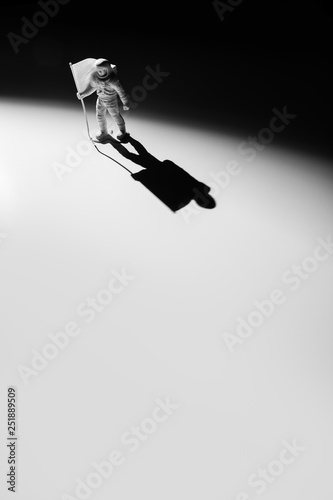 Fototapeta Naklejka Na Ścianę i Meble -  Lone Generic White Astronaut Figurine with American Flag in dramatic lighting