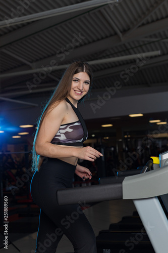 Attractive young sports woman is working out in gym. Doing cardio training on curve treadmill. Running on non-motorized treadmill.