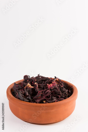 petals of dry hibiscus tea in the clay pot isolated on white background