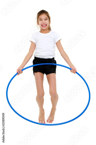A little girl in a white T-shirt performs exercises with a hoop.