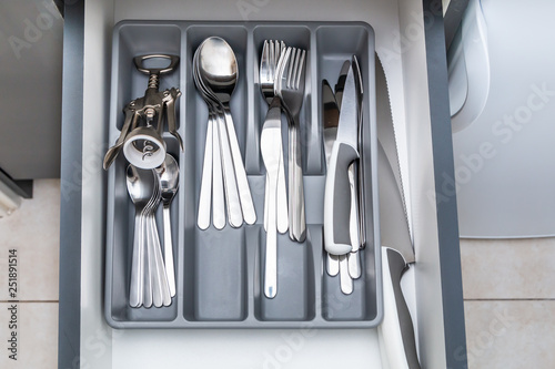 Opened drawer with shiny silver cutlery in modern kitchen. Close up.