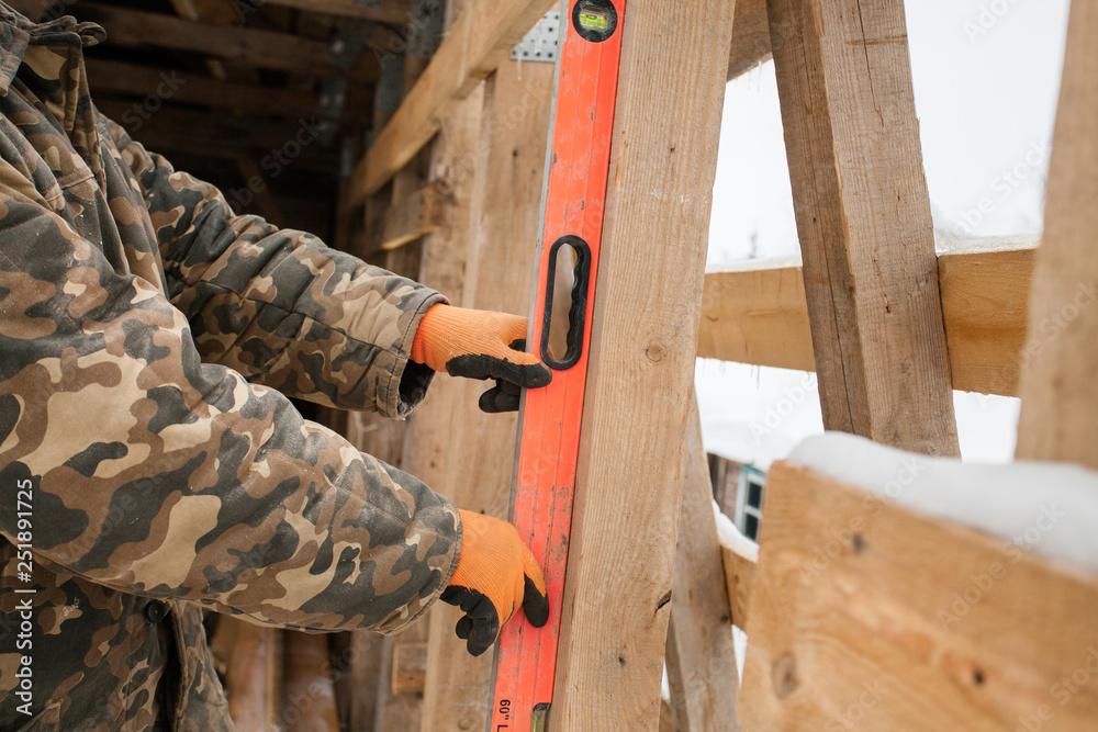 Carpenter measure the level of roof. Horizontal. Man builds a roof of wooden planks. Attic renovation. Building construction outdoor. Countryside house. Farm householding. Carpenter measure the level of roof. Horizontal. Man builds a roof of wooden planks. Attic renovation. Building construction outdoor. Countryside house. Farm householding.