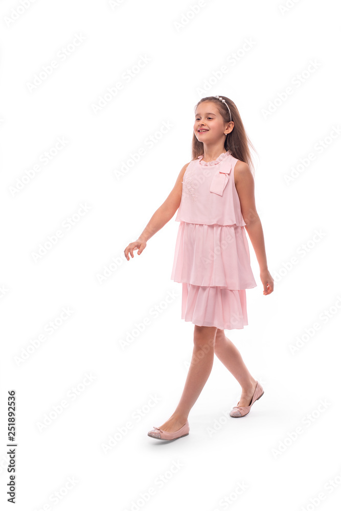 Studio shot of a little smiling girl wearing pink sundress on a white background. She goes with a good mood, good mood Studio shot of a little smiling girl wearing pink sundress on a white background. She goes with a good mood, good mood