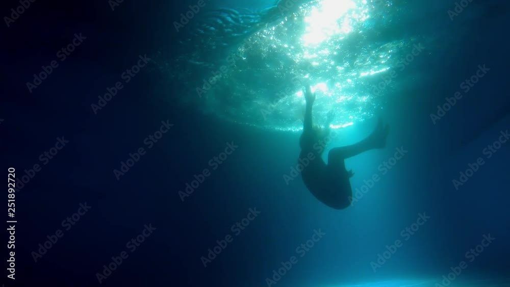 Woman jumping into a floodlit pool at night