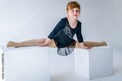 A little girl performs a gymnastic twine in weight. The concept of fitness and sports and a healthy lifestyle. Photo on white background, isolated