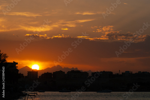 Sunset at city of Hurghada with buildings and mountains silhouette