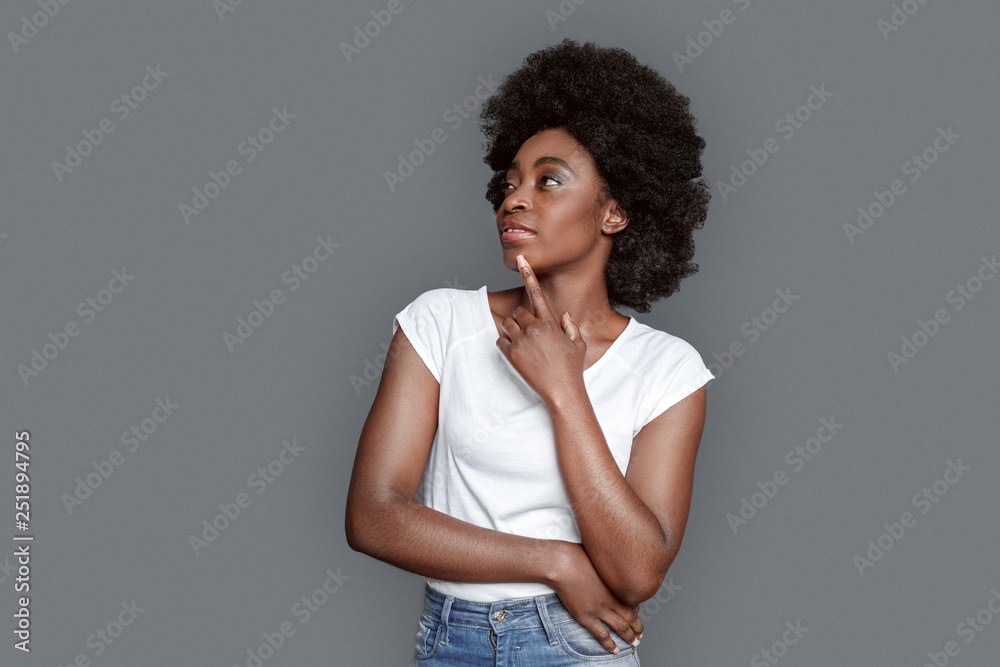 Young woman standing isolated on gray looking at space aside pensive Young woman standing isolated on gray looking at space aside pensive