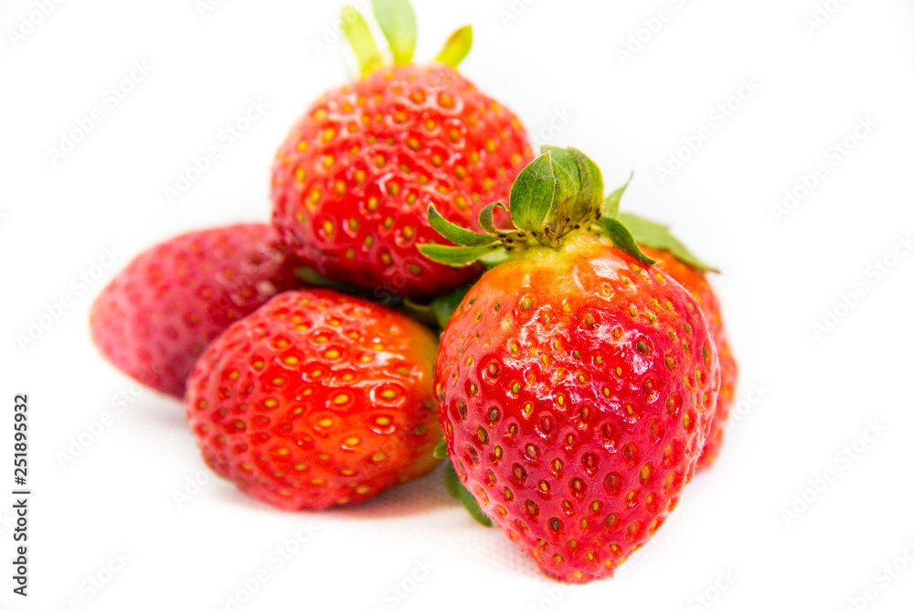 Several red strawberries with leaves on a white background Several red strawberries with leaves on a white background