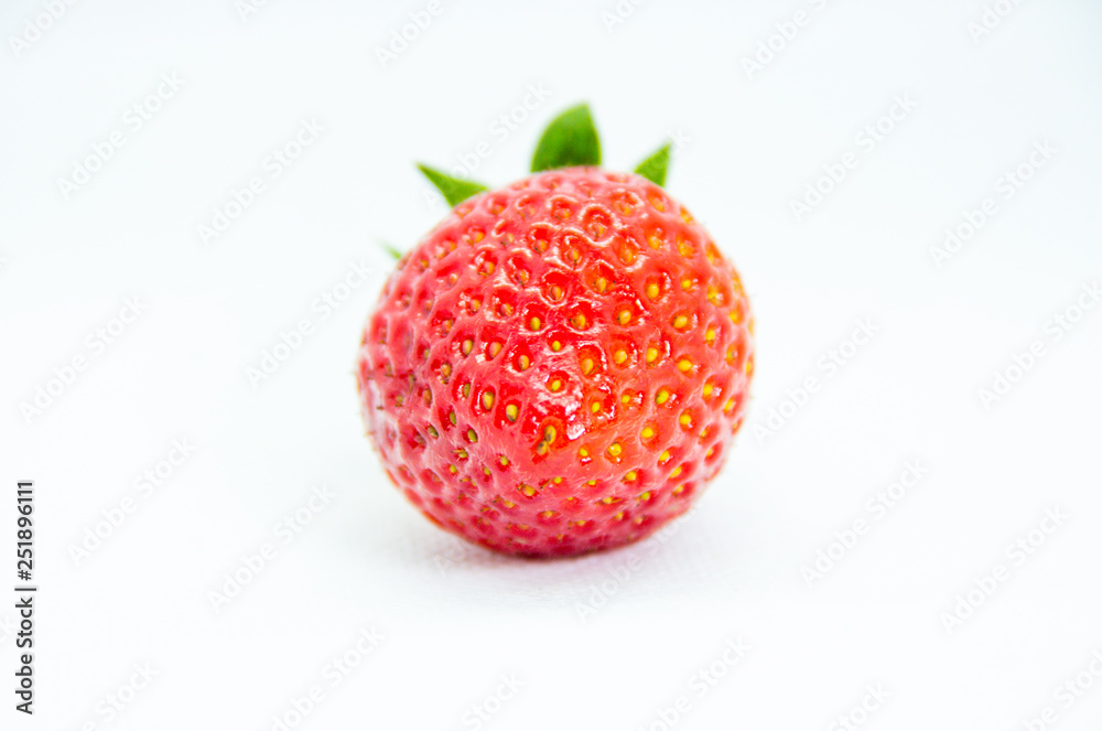 One red strawberry with leaves on white background One red strawberry with leaves on white background