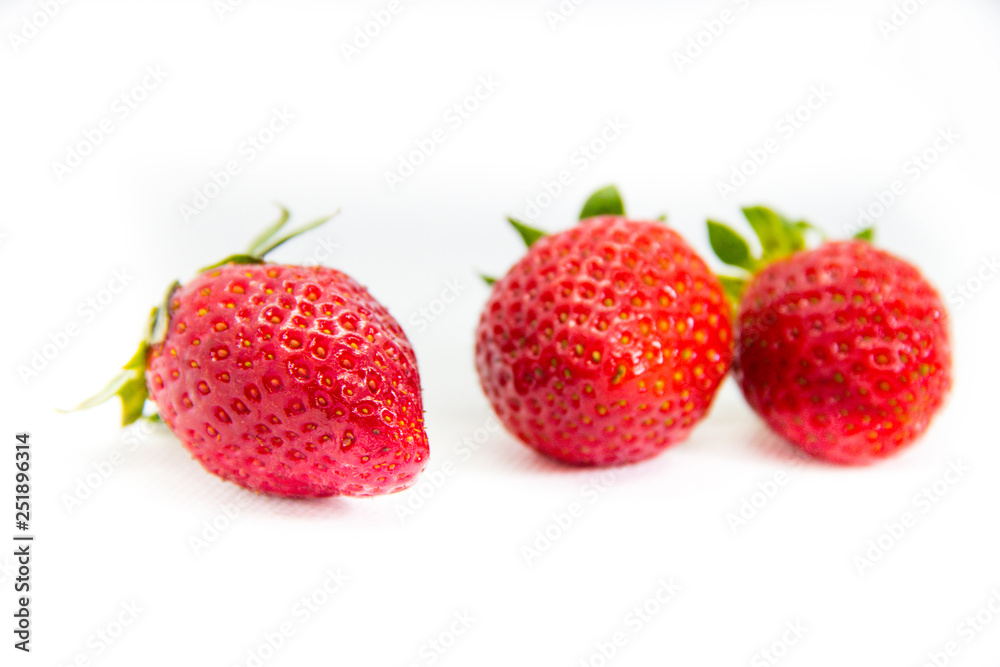 Several red strawberries with leaves on a white background Several red strawberries with leaves on a white background