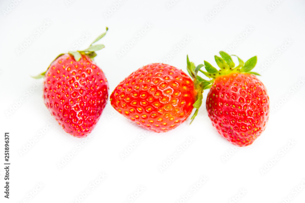 Several red strawberries with leaves on a white background Several red strawberries with leaves on a white background
