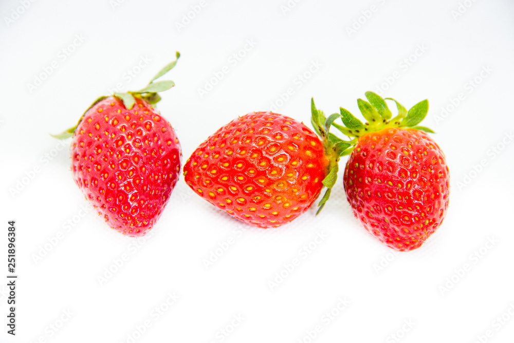 Several red strawberries with leaves on a white background Several red strawberries with leaves on a white background