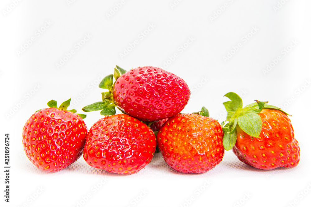 Several red strawberries with leaves on a white background Several red strawberries with leaves on a white background