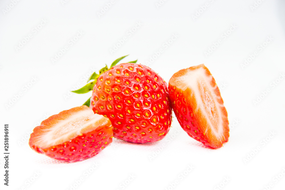Whole and cut in half red strawberry and cut with leaves on white background Whole and cut in half red strawberry and cut with leaves on white background