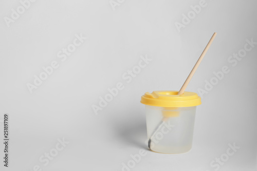 Paint brush in cup of water on light background. Space for text