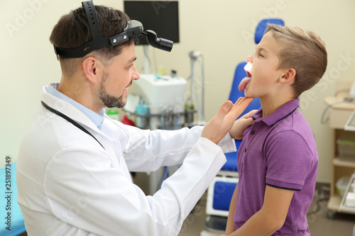 Male otolaryngologist examining little child in hospital