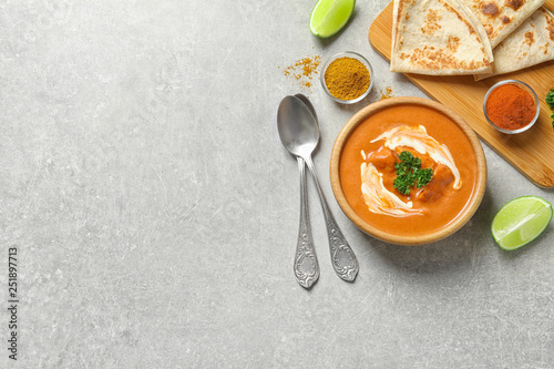 Delicious butter chicken served on grey table, top view with space for text. Traditional indian Murgh Makhani
