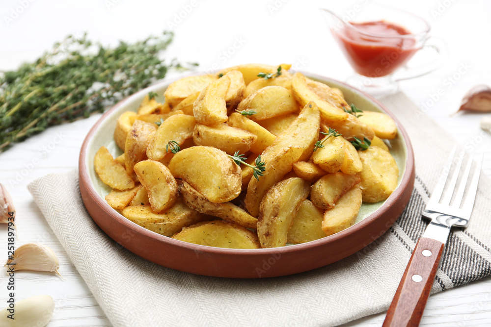 Plate with tasty baked potato wedges on wooden table Plate with tasty baked potato wedges on wooden table