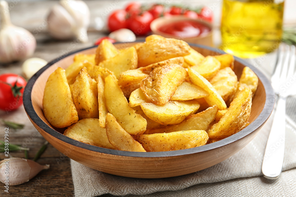 Plate with tasty baked potato wedges on wooden table Plate with tasty baked potato wedges on wooden table