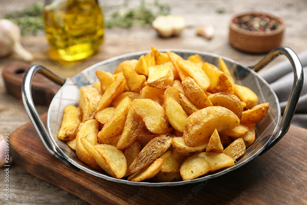 Frying pan with tasty baked potato wedges on wooden table Frying pan with tasty baked potato wedges on wooden table