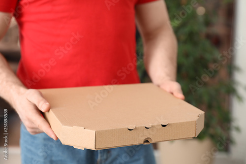 Courier with pizza box on blurred background, closeup. Space for text © New Africa