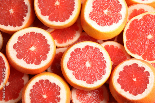 Many sliced fresh grapefruits as background  top view