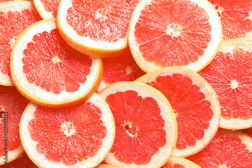 Many sliced fresh grapefruits as background, top view