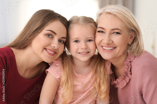 Portrait of young woman, her mature mother and daughter indoors