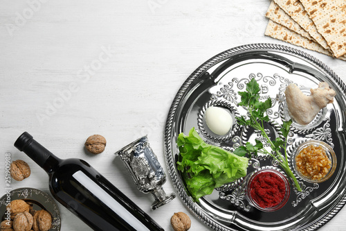 Flat lay composition with symbolic Passover (Pesach) items and meal on wooden background, space for text photo