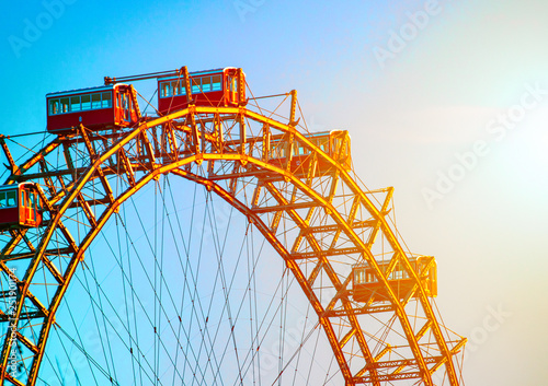 Ferris wheel in the rays of setting sun, blue sky backgroung. Vienna, Austria