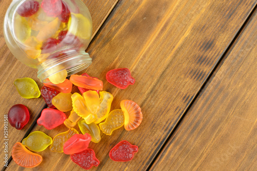 Colored gummy fruit candy spilled, on a brown wooden table