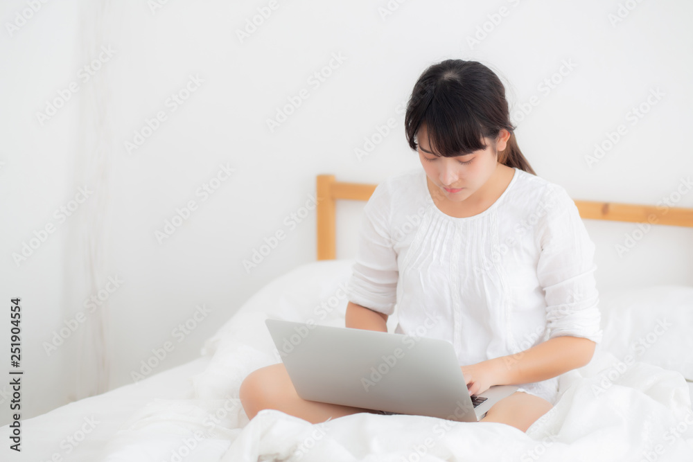 Portrait of beautiful asian young woman sitting on bed using laptop computer at bedroom for leisure and relax, freelance with girl working notebook, communication and lifestyle concept. Portrait of beautiful asian young woman sitting on bed using laptop computer at bedroom for leisure and relax, freelance with girl working notebook, communication and lifestyle concept.