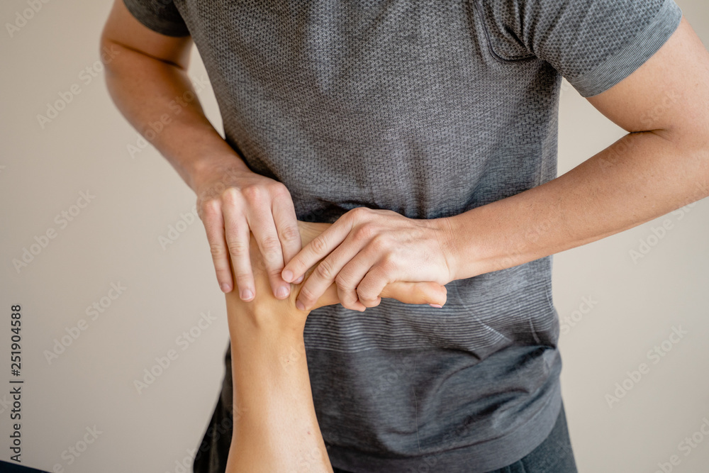 Masaje de fisioterapia en tobillo tratando a deportista