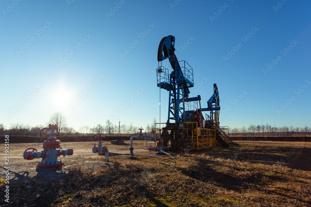 oil production tower while working against the bright sun and blue sky oil production tower while working against the bright sun and blue sky