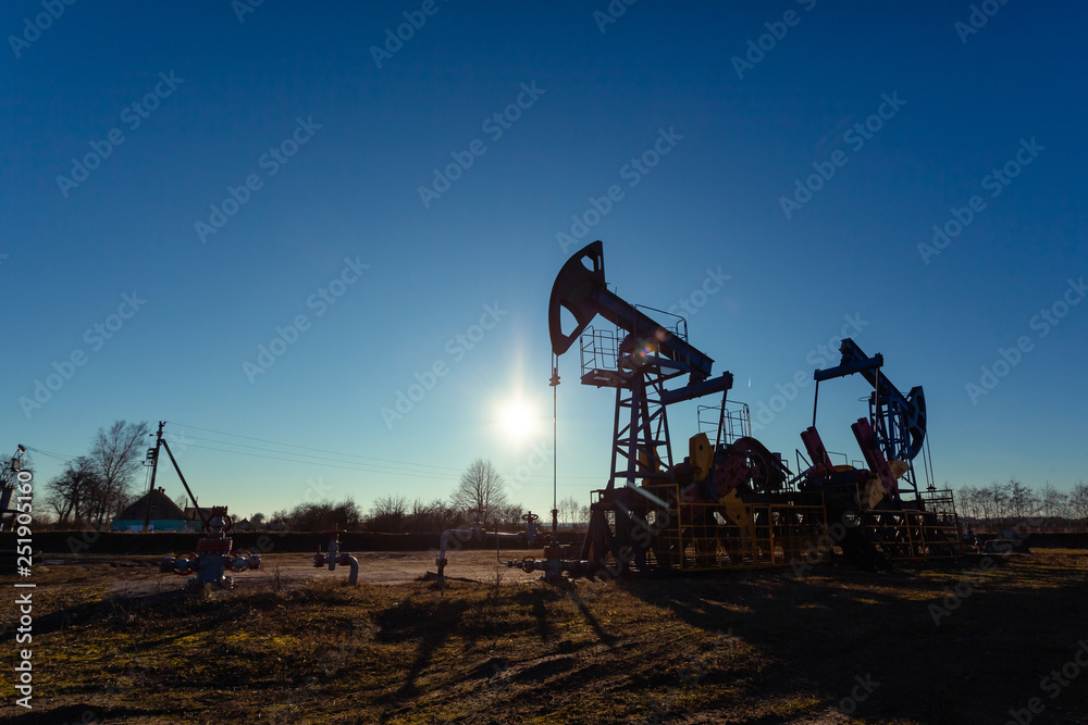 oil production tower while working against the bright sun and blue sky oil production tower while working against the bright sun and blue sky